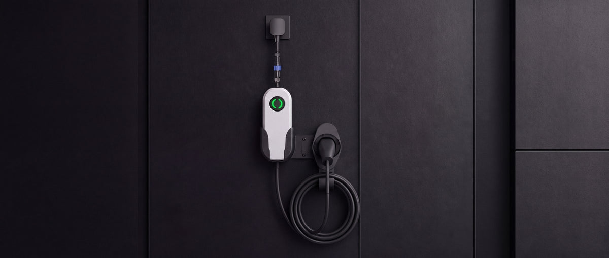 A2Z Nebula Mini portable EV charger mounted on a dark wall, plugged into an outlet, cable coiled on its holster